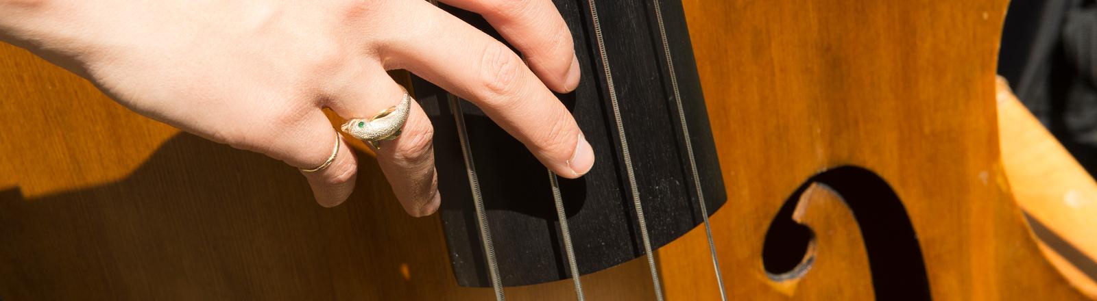 A close up of a student playing the bass (strings)