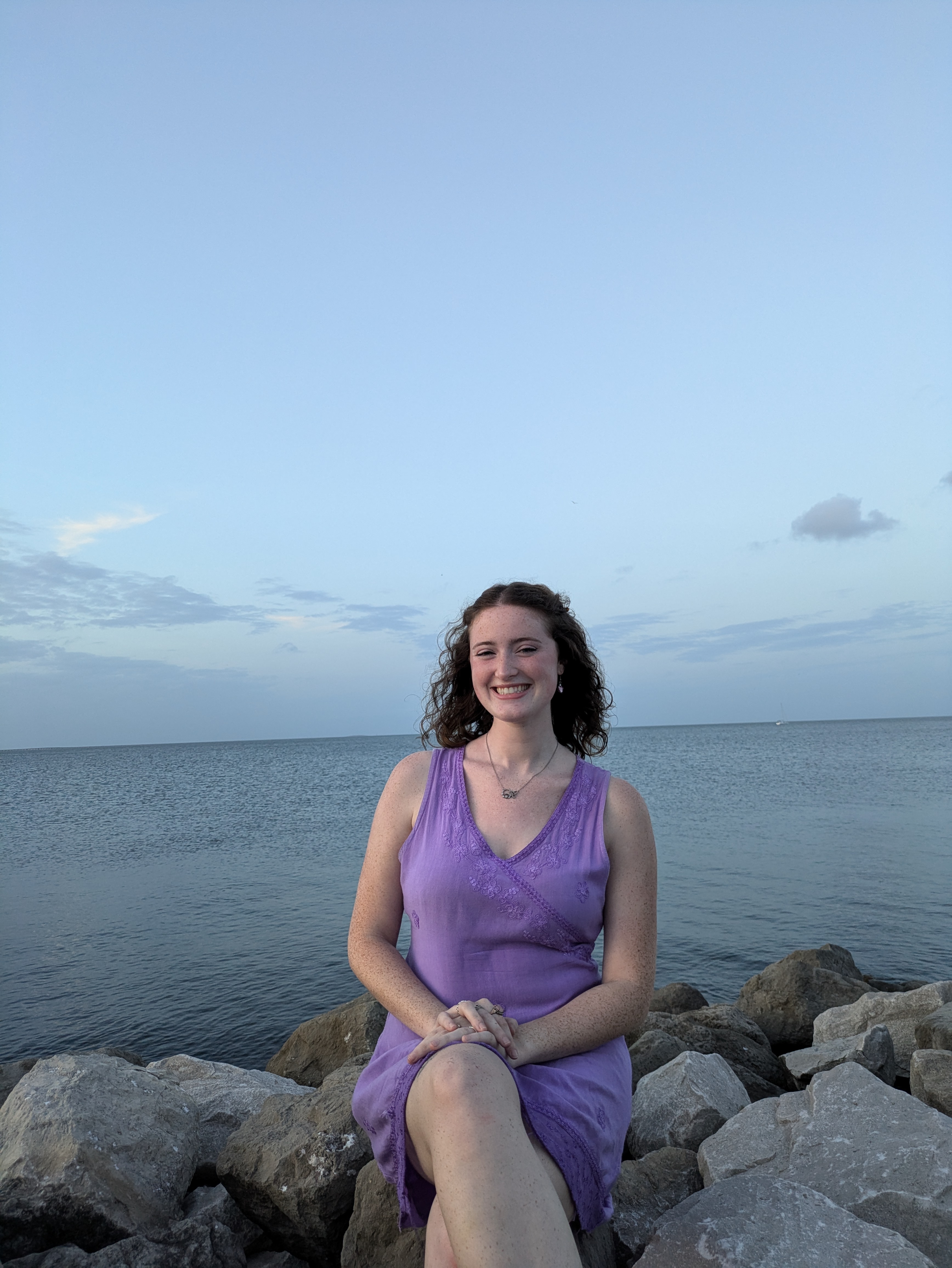 A photo of Riley Jennings sitting in front of the ocean.